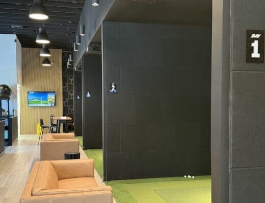 A private simulator bay with seating at Tee Box Delray in Delray Beach, FL